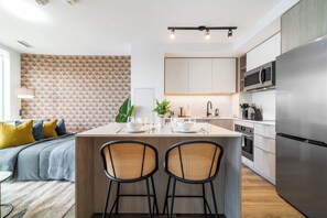 A modern kitchen with a central island, stainless steel appliances, and a dining area with a sofa and chairs.