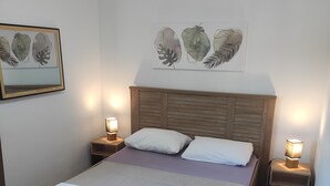 Ein Schlafzimmer mit einem hölzernen Bett, weißen Kissen, einem Holz-Kopfende und zwei Nachttischen mit Lampen.