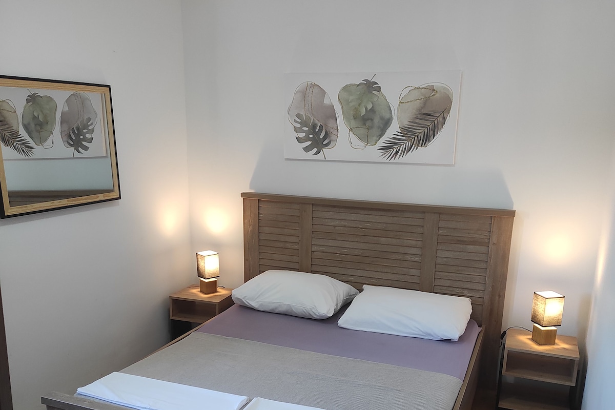 Un dormitorio con una cama de madera, almohadas blancas, un cabecero de madera y dos mesitas de noche con lámparas.