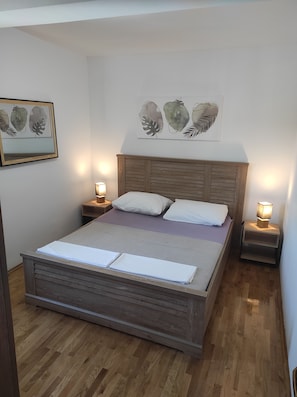 Un dormitorio con una cama de madera, almohadas blancas, un cabecero de madera y dos mesitas de noche con lámparas.