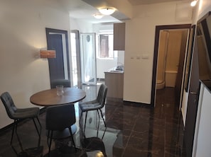 A dining area with a round table and four chairs, a kitchen with a sink, and a bathroom with a toilet.