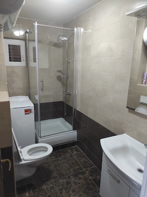 Un baño con ducha de vidrio, inodoro y lavamanos.