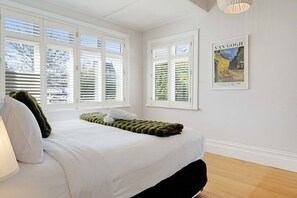 Une chambre à coucher avec un lit, des murs blancs et une fenêtre avec des stores.