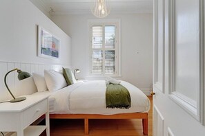 A bedroom with a bed, bedside tables, a desk, a window with blinds, and a hanging light fixture. - Grafton Garden 4BR Retreat near Domain (Auckland CBD)
