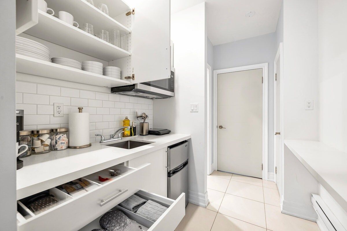 A modern kitchen with white cabinetry, a built-in oven, and a stainless steel range hood.