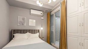 A hotel room with a bed, a nightstand, a wall-mounted air conditioner, a framed certificate, and a sliding glass door with curtains. - Tonight Homestay Taikoo Hui Shanghai (SHANGHAI)