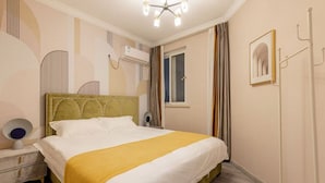 A hotel room with a bed, bedside table, lamp, air conditioning unit, window, curtains, and a framed picture on the wall. - Tonight Homestay Taikoo Hui Shanghai (SHANGHAI)
