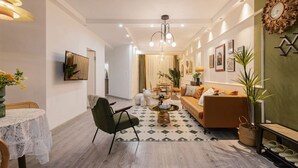 A modern living room with a sofa, a dining table, and a coffee table. There is a wall with framed pictures and a decorative clock. - Tonight Homestay Taikoo Hui Shanghai (SHANGHAI)