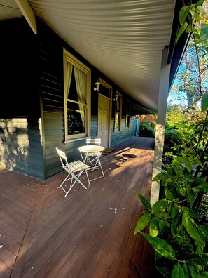 Eine überdachte Veranda mit Tisch und Stühlen, einer Tür und Fenstern.