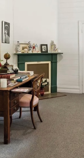 Ein Zimmer mit Schreibtisch, Stuhl, Büchern, einem Globus und einem Kamin mit Figuren.
