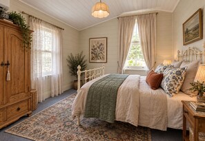 Ein Schlafzimmer mit einem Bett, einem Holzschrank, einer Topfpflanze und einem Bild an der Wand.