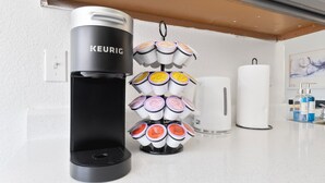 Une machine à café Keurig avec un porte-tasse et un distributeur de serviettes en papier blanches, posés sur un comptoir de cuisine.