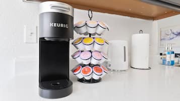 A Keurig coffee machine with a mug holder and a white paper towel dispenser on a kitchen counter.