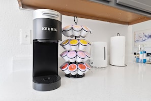 Una cafetera Keurig con un portavasos y un dispensador de toallas de papel blancas sobre una encimera de cocina.