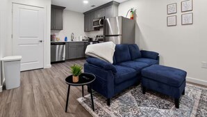 Un salon moderne avec un canapé bleu, une petite table d’appoint ornée d’une plante et un tapis à motifs.