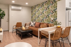 A modern living room with a sofa, chairs, a dining table, and a patterned wallpaper. - Boho 2BR | Monthly Stays | Quiet East Ottawa (Ottawa)