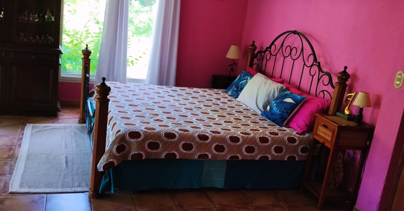 Une chambre à coucher avec un lit, une table de chevet, une lampe et une fenêtre avec des rideaux.