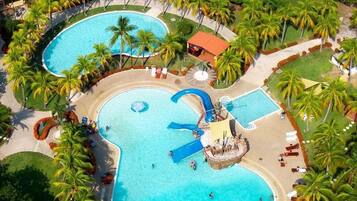 Un resort con dos piscinas grandes, palmeras y un tobogán de agua.
