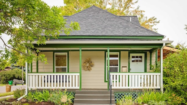 Een huis met een groene veranda, een voordeur en het nummer 301 op de gevel.