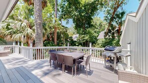 A covered outdoor deck with a dining table and chairs, surrounded by a white railing, and a barbecue grill. - New to VRBO, 5BR Palmetto Dunes, 7.5 Min Walk To Beach, Private Pool (Hilton Head Island)
