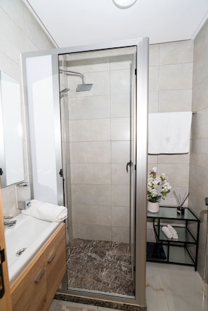 A modern bathroom with a glass-enclosed shower, a white sink, and a marble-tiled floor. - Amazing 3-bedroom apartment with AC in charming Tangier (Tangier)