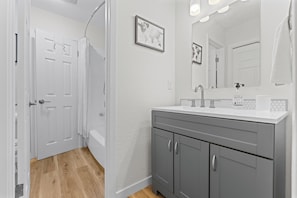 A bathroom with a white vanity, a large mirror, and a framed world map on the wall. - F1 Ready - Heart of South Austin - 2B/1.25BA - King Bed - Fast WiFi - Yard (Austin)
