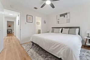 Un dormitorio con una cama grande, un ventilador de techo y vista a otra habitación.