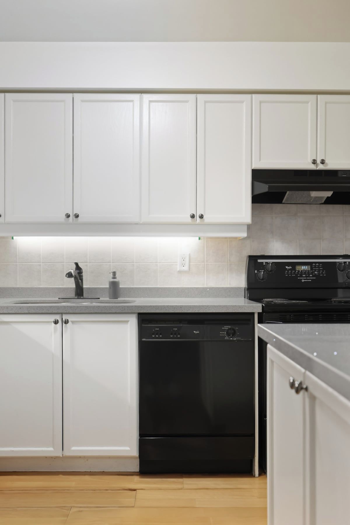 A kitchen with white cabinets, a black dishwasher, and a black stove.
