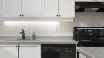 A kitchen with white cabinets, a black dishwasher, and a black stove.