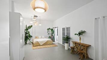 A spacious bedroom with a large bed, a dining area with a table and chairs, and multiple hanging lights.