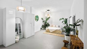Une chambre à coucher moderne avec un lit, des tables de chevet, un miroir et des plantes en pot.