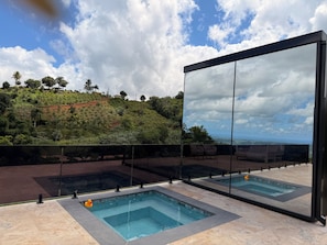 A modern outdoor pool area with clear views of a hilly landscape.