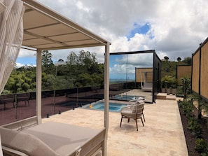 A rooftop terrace with a swimming pool, lounge chairs, and a view of the surrounding landscape.