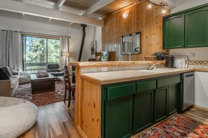 A modern kitchen with wooden cabinets, a large island, and a view of the outdoors. - Tyrolean Village 213 Two-level 2BR/2BA Mammoth townhome near lifts, with mountain views. (Mammoth Lakes)