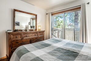 Une chambre à coucher avec un grand lit, une commode en bois, un miroir et une fenêtre avec des rideaux.