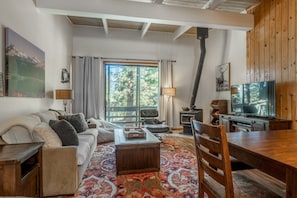 A cozy living room with a sofa, coffee table, TV, and a fireplace. - Tyrolean Village 213 Two-level 2BR/2BA Mammoth townhome near lifts, with mountain views. (Mammoth Lakes)