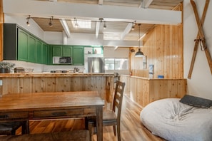 A rustic kitchen with wooden cabinets, a dining table, and a cozy seating area with a cushion. - Tyrolean Village 213 Two-level 2BR/2BA Mammoth townhome near lifts, with mountain views. (Mammoth Lakes)