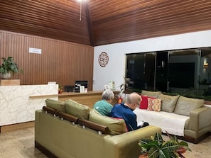 Un área de recepción con techo de madera, un mostrador de recepción y dos sofás con cojines.