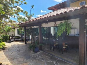 An outdoor patio with stone flooring, wooden furniture, and potted plants. - Costa do Sol By MN Hoteis (Búzios)