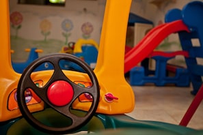 A colorful children's ride with a steering wheel and a red slide. - Costa do Sol By MN Hoteis (Búzios)