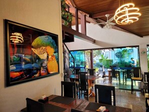 Un espace de restauration intérieur avec des tables et des chaises, un ventilateur de plafond et une grande fenêtre donnant sur l’extérieur.