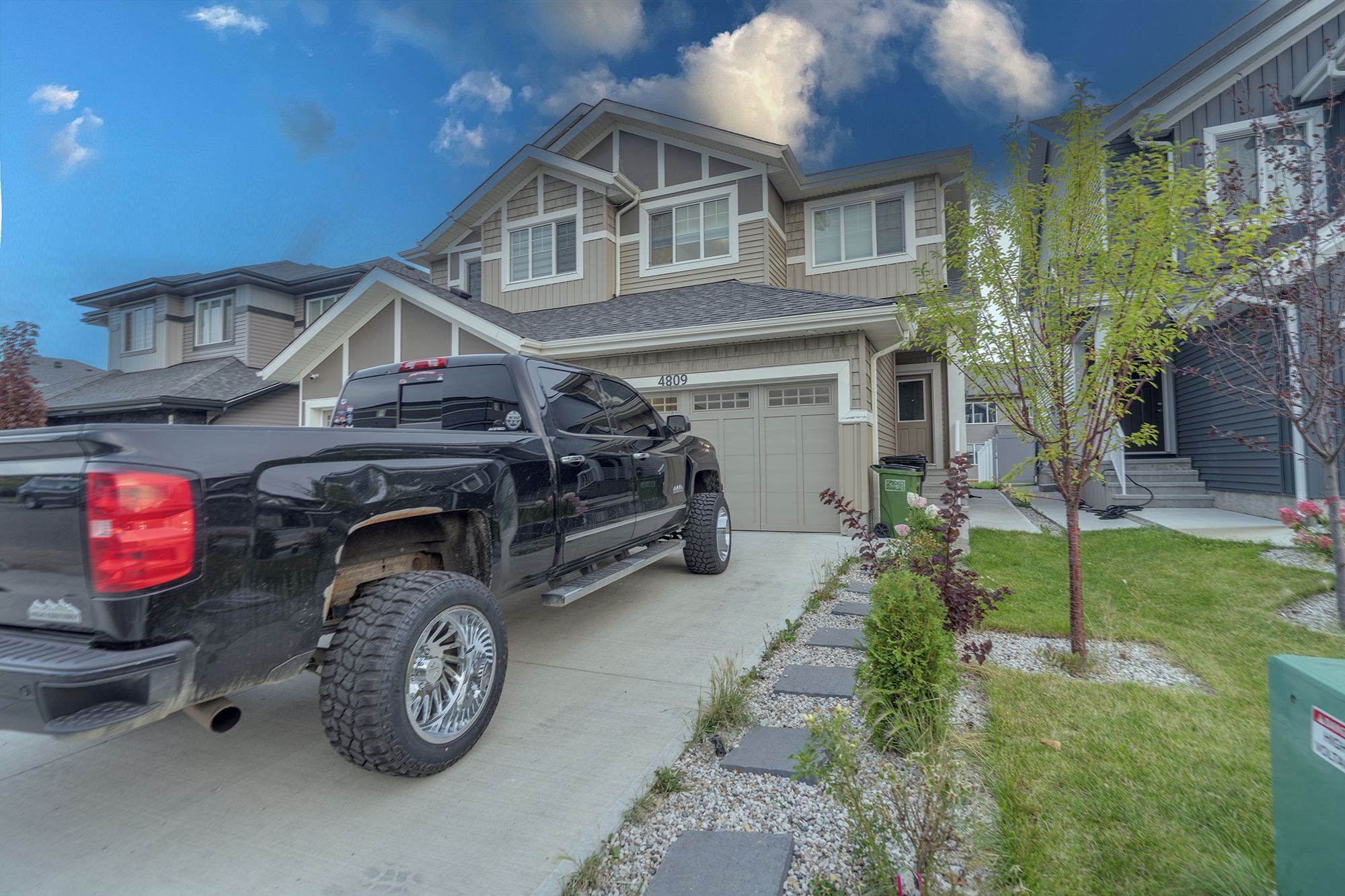 Een oprit bij een woning met een zwarte pick-up truck geparkeerd voor een huis met garage nummer 4809.