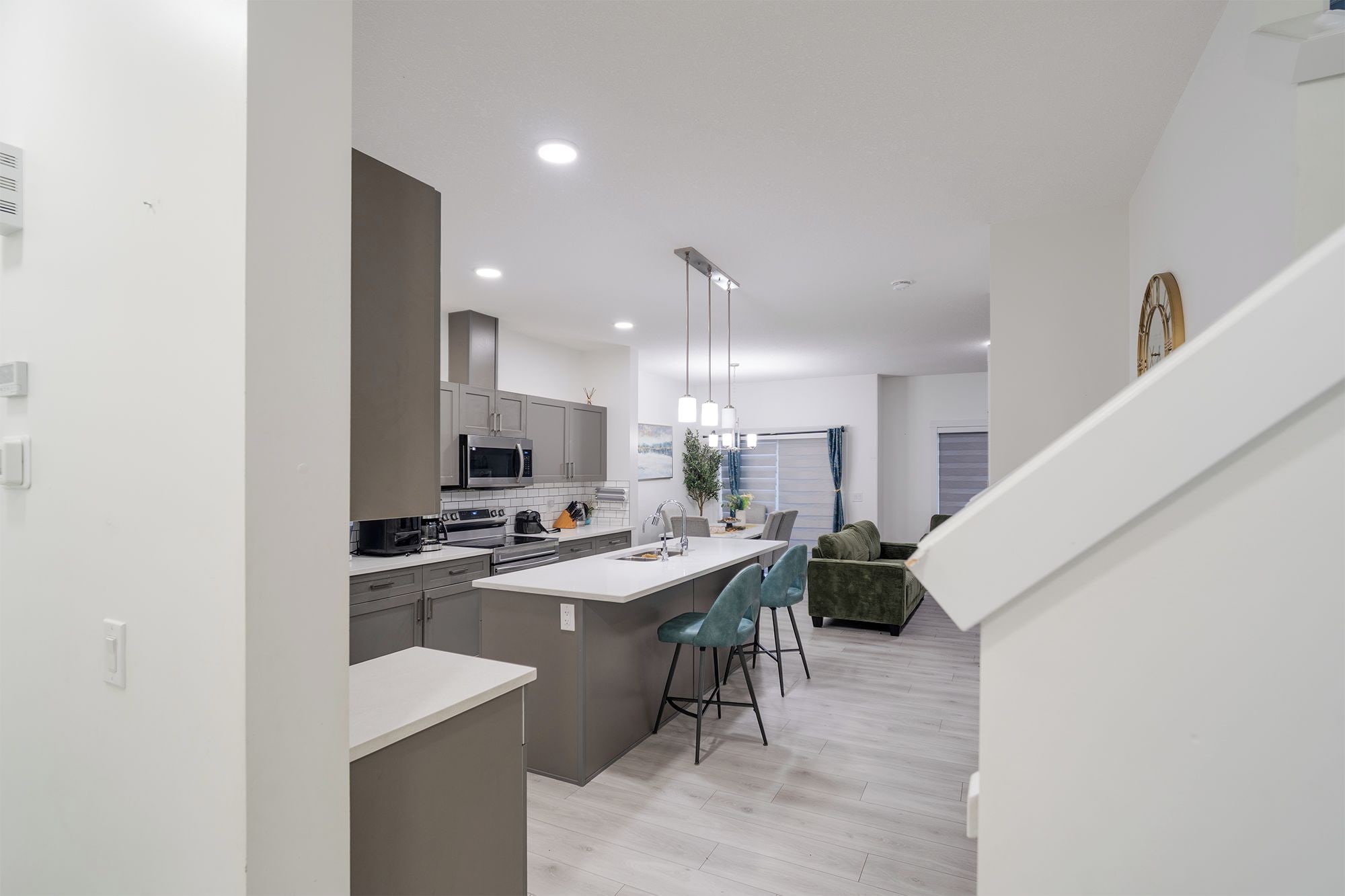 A modern kitchen with a central island, bar stools, and a dining area with a sofa.