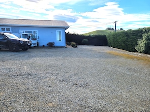 Une propriété résidentielle avec une allée en gravier, une maison bleue et un camion garé.
