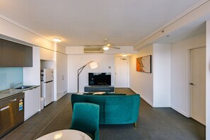 Ein modernes Wohnzimmer mit einer Couch, einem Fernseher und einem Essbereich mit Tisch und Stühlen.