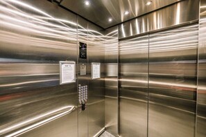 Ein Fahrinnenraum mit Metallwänden, einer Bedienkonsole mit Tasten und Hinweisschildern.