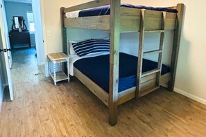 Ein Etagenbett mit Holzbettgestell, ein kleiner Nachttisch und eine dunkelbraune Matratze.