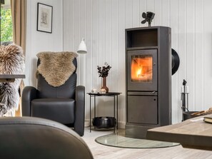 A modern living room with a black leather chair, a glass coffee table, a fireplace, and a framed picture on the wall. - "Nanook" -  from the sea by Interhome (Hadsund)