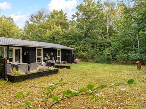 Ein Haus mit überdachter Terrasse, Gartenmöbeln und einem Garten.