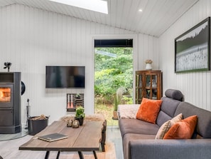 Ein modernes Wohnzimmer mit Kamin, einer Couch, einem Couchtisch und einem Fernseher.